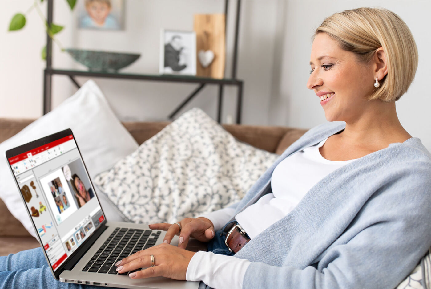 Eine Person arbeitet am Laptop und gestaltet ein CEWE FOTOBUCH. Ihr Kleidungsstil ist lässig und sie sitzt auf einem Sofa.