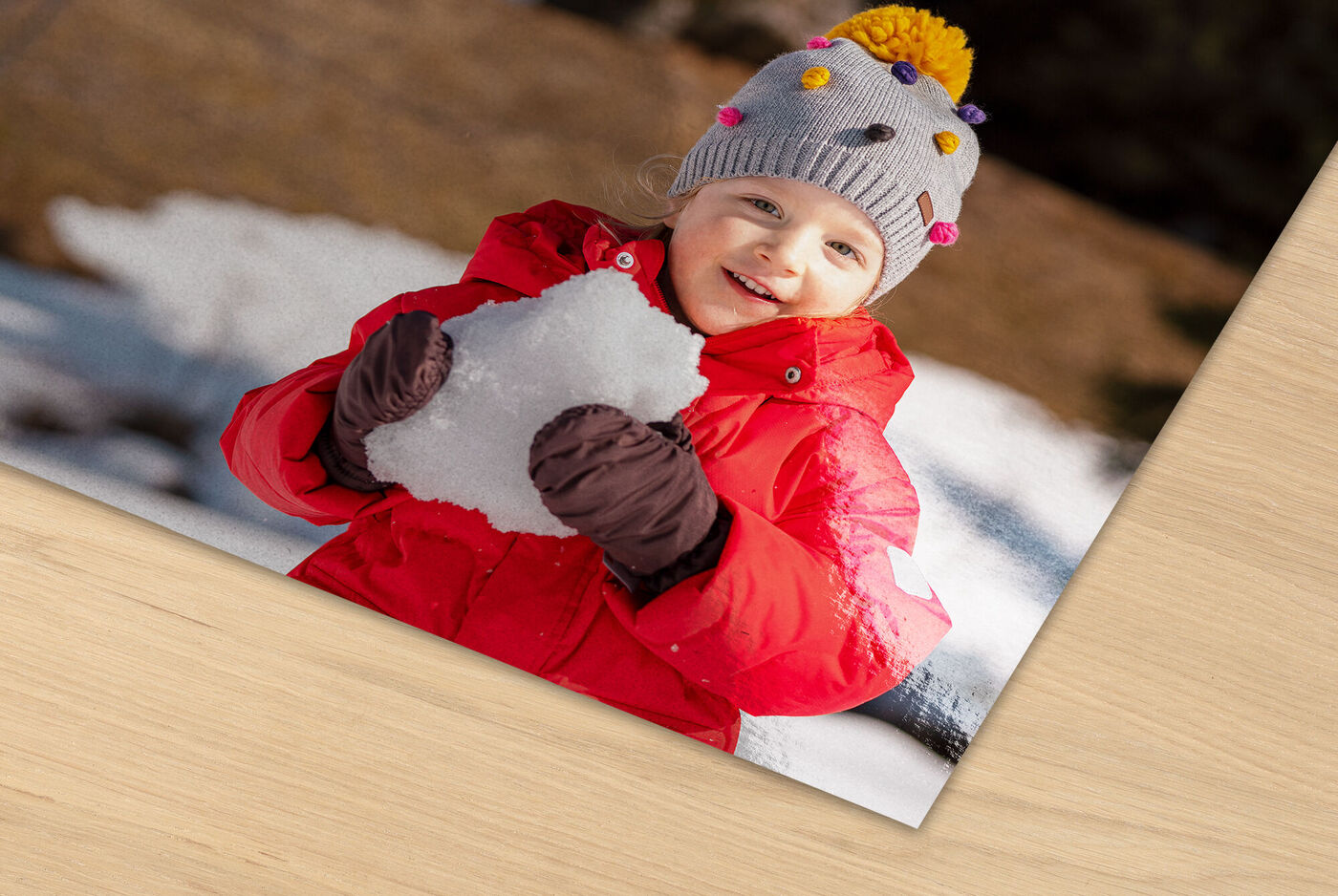 Kind in roter Jacke mit Schnee in den Händen