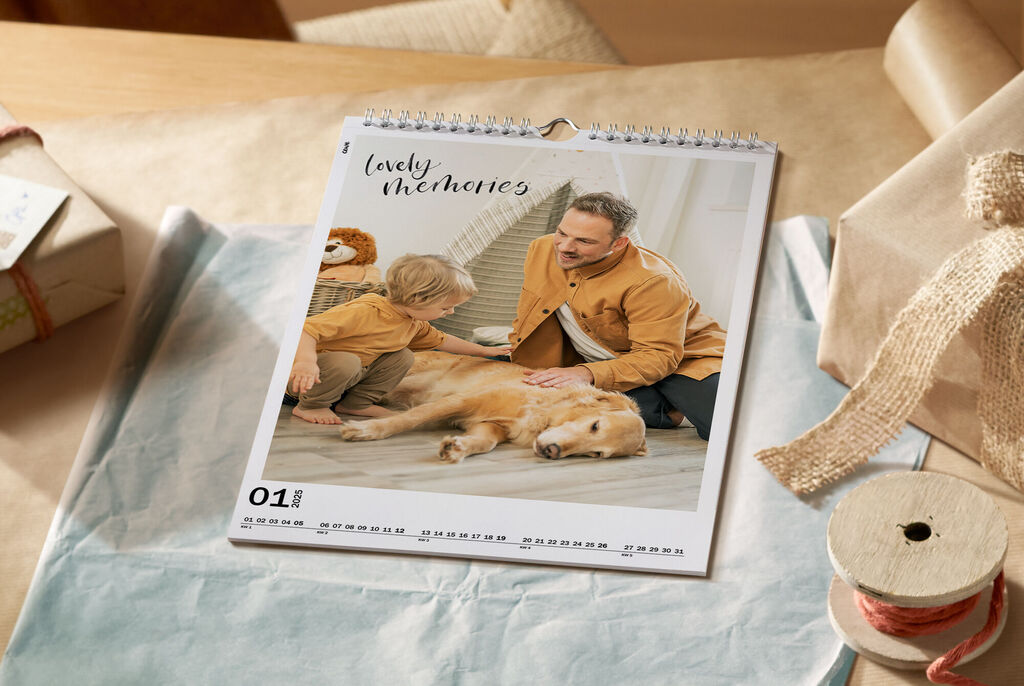 Ein kinderfreundlicher CEWE Kalender mit einem Hund, einem Kind und einem Erwachsenen, die zusammen spielen.