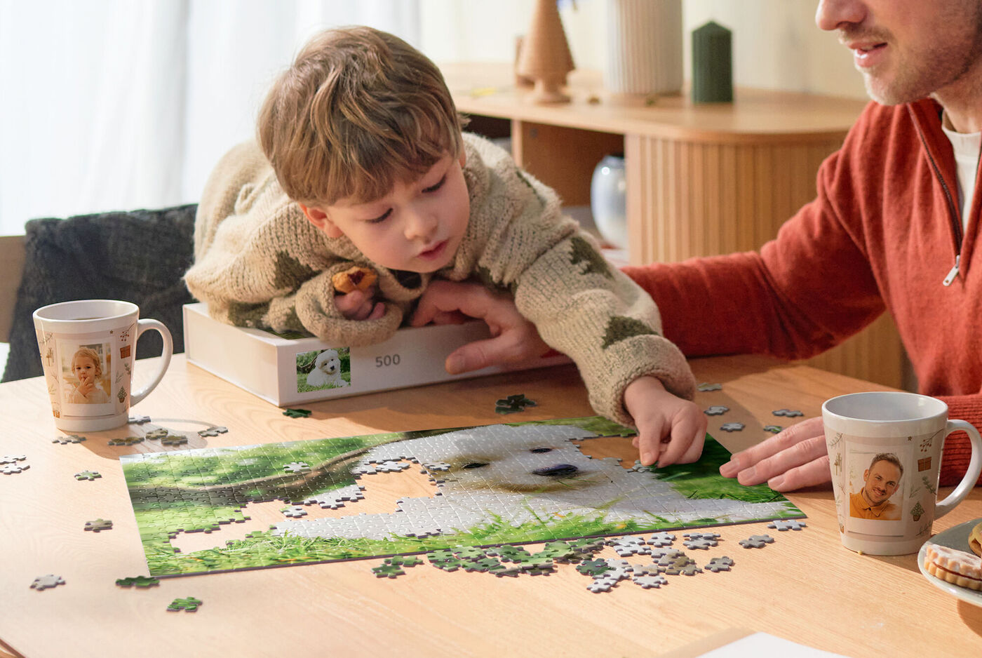 Kind und Erwachsener legen gemeinsam ein Puzzle mit Hundemotiv auf einem Holztisch, umgeben von individuell gestalteten Fototassen.