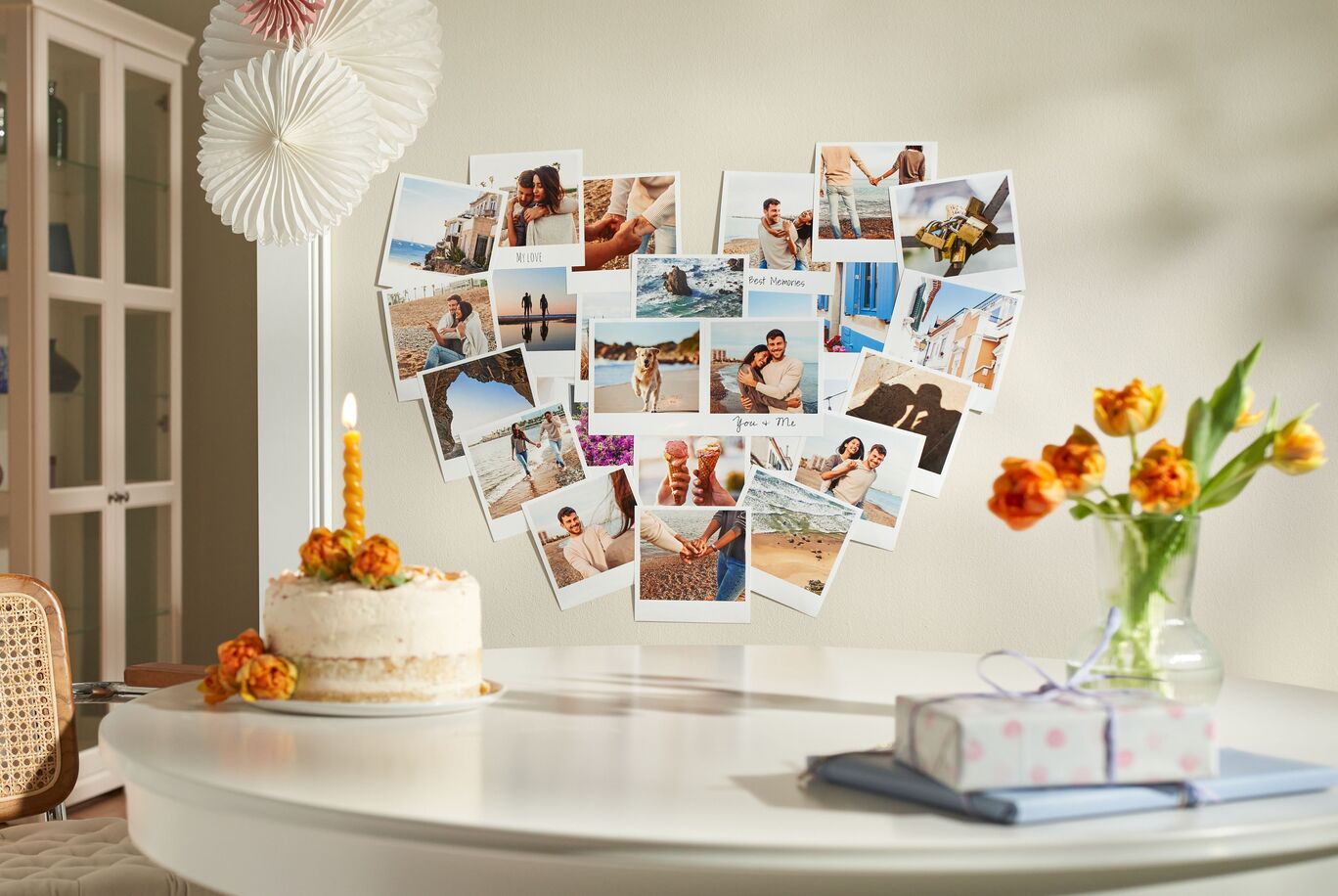 Eine hübsche Tischdekoration mit Fotografien in Herzform auf einem Tisch, umgeben von einer Torte und Blumen.