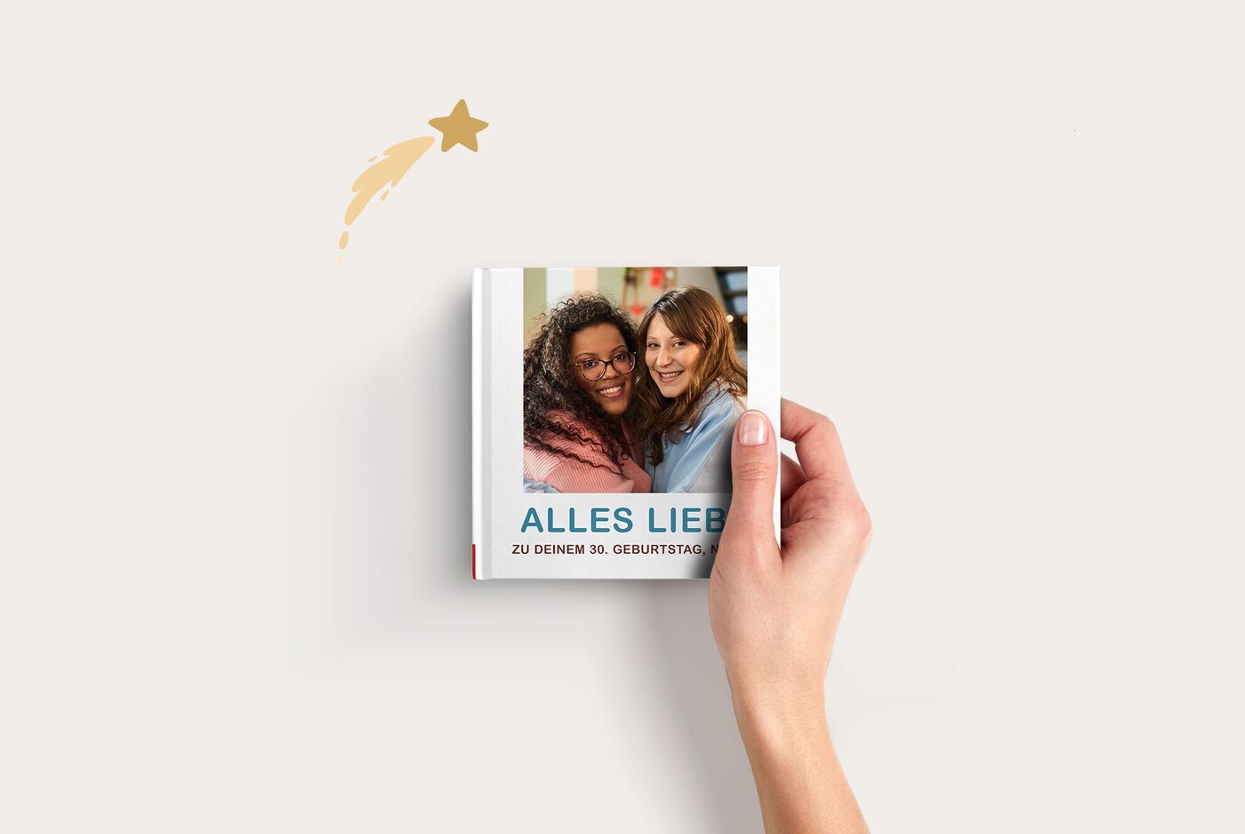 Hand hält ein CEWE Fotobuch Compact Quadratisch mit zwei Personen, die sich umarmen, und Schriftzug "ALLES LIEBE"