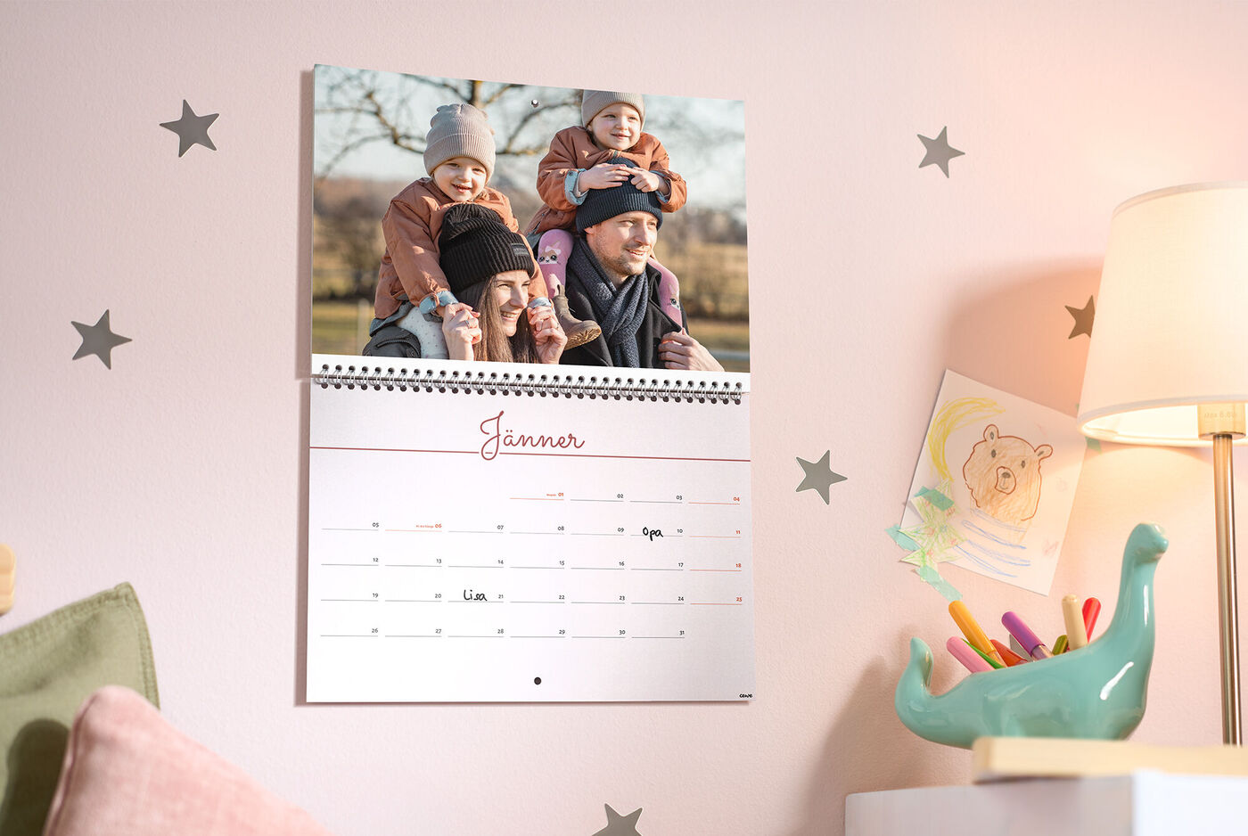 Geburtstagskalender im Monat „Jänner“ im Kinderzimmer, mit Sternen, warmem Lampenlicht und fröhlichem Dino‑Stiftehalter.