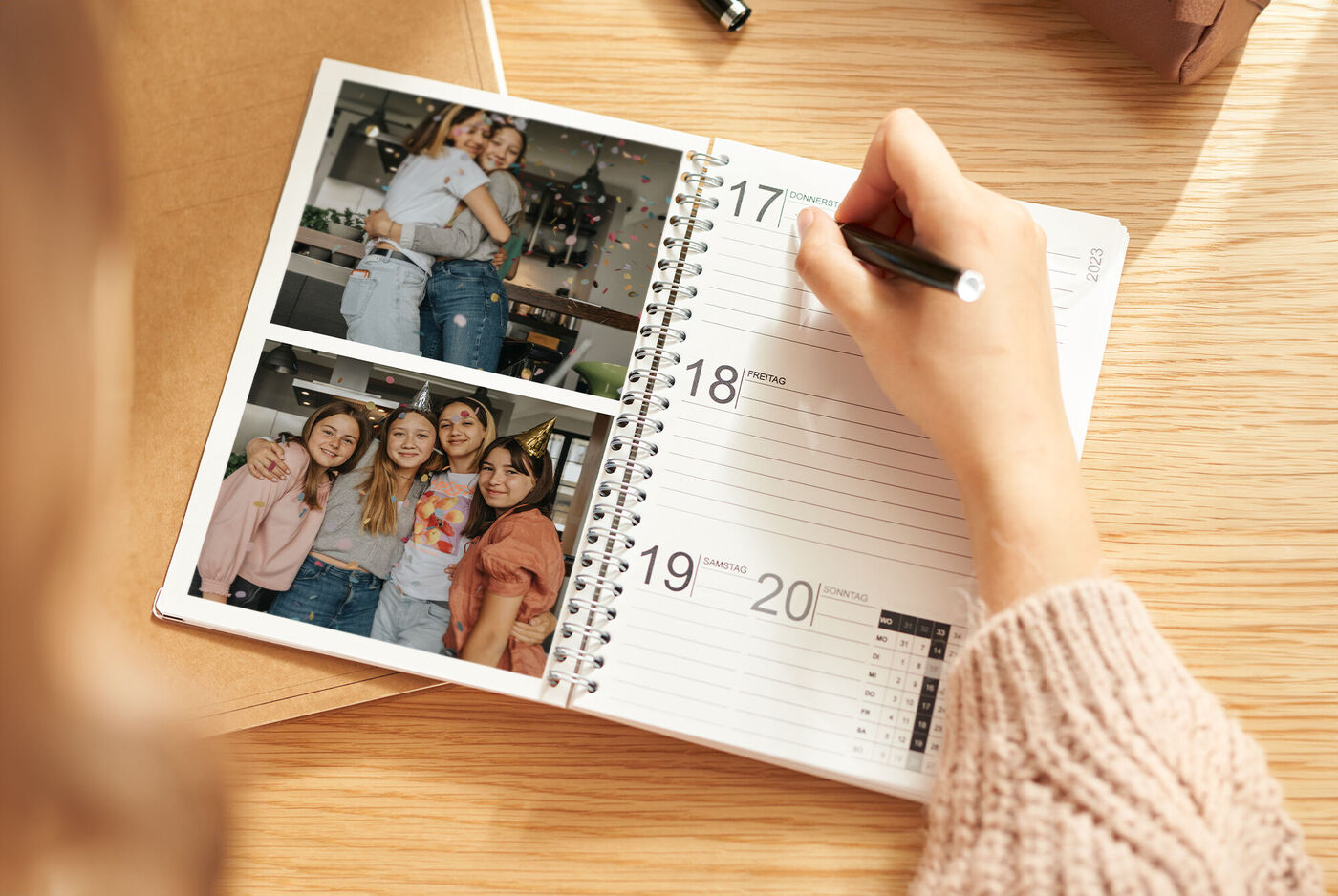 Herzmomente im Alltag: Hand schreibt in einen Terminplaner, daneben zwei Freundschaftsfotos – Lächeln, das durch die Woche trägt.