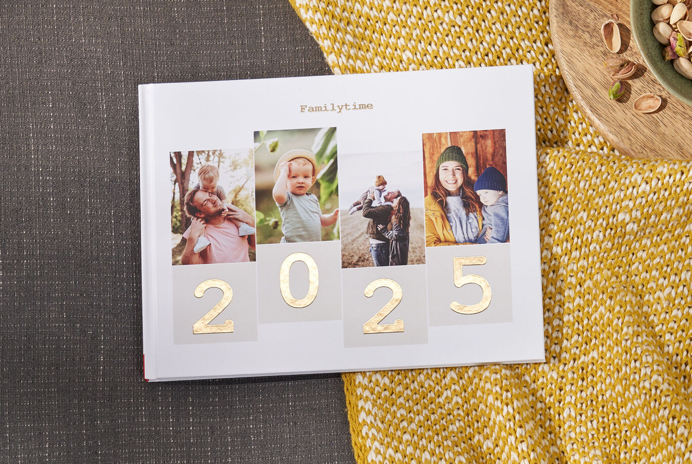 Ein CEWE FOTOBUCH mit Fotos von glücklichen Familienmomenten und der Jahreszahl 2024.