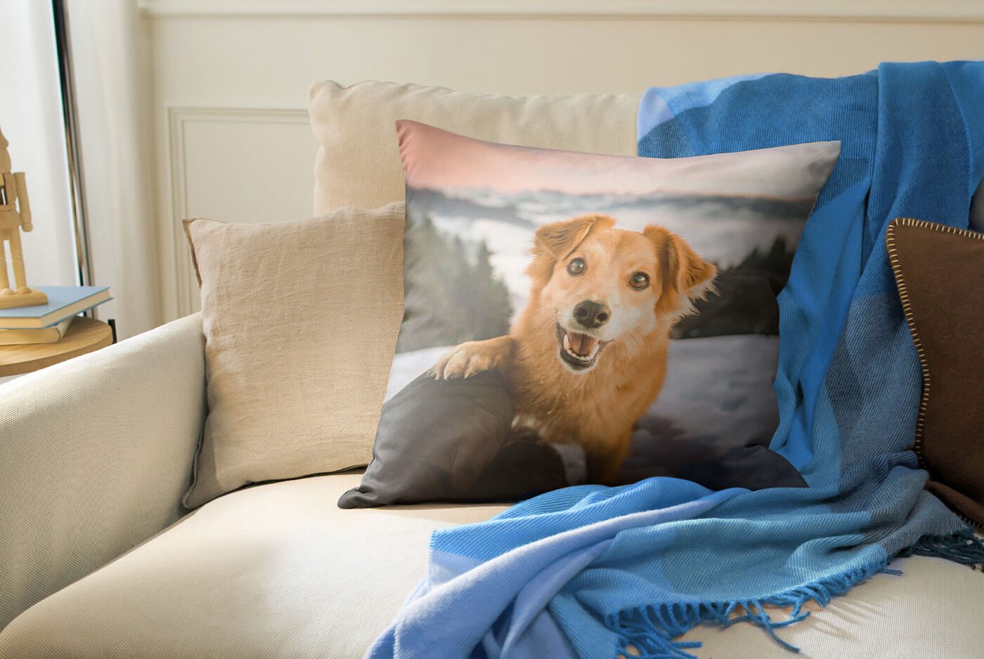 Personalisiertes Kissen mit braunem Hundemotiv liegt auf einem Sofa, umgeben von Decken und weiteren Kissen.