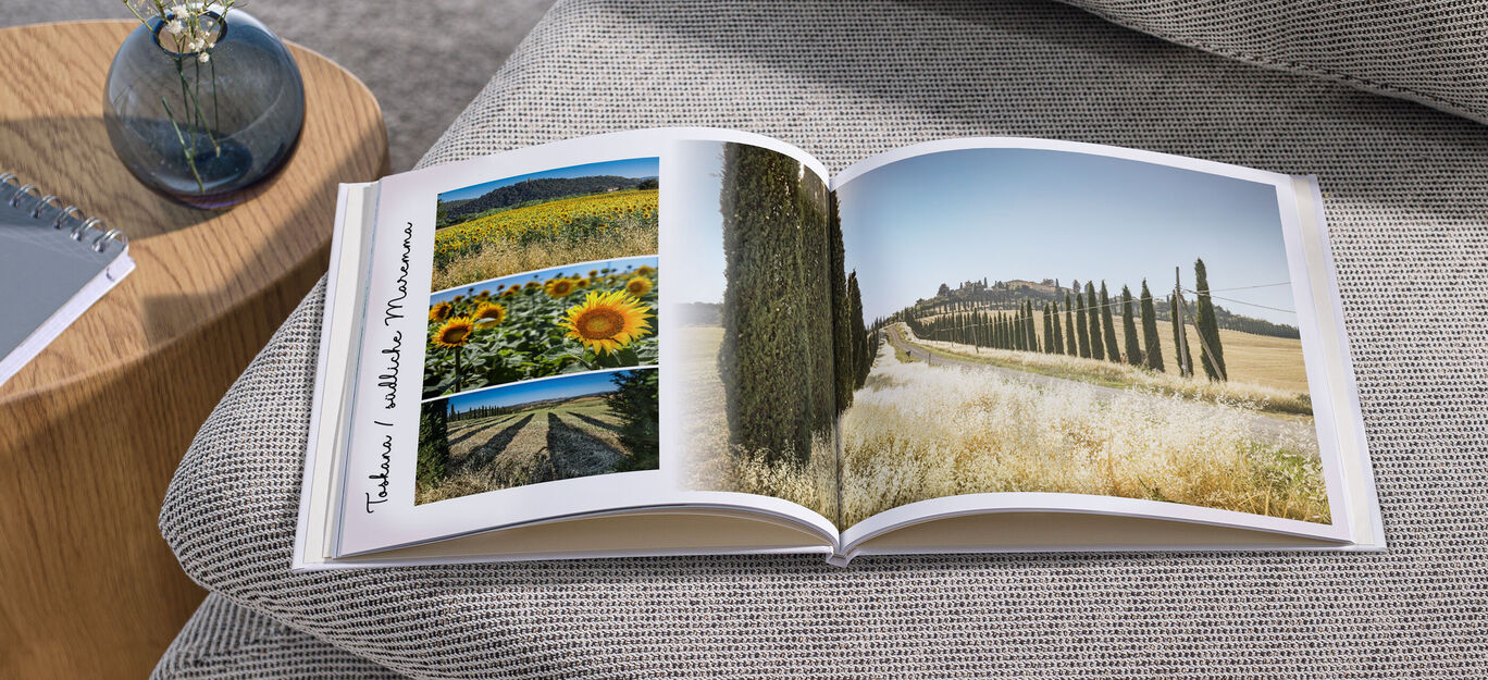 Geöffnetes CEWE FOTOBUCH mit Sonnenblumen und italienischer Landschaft.