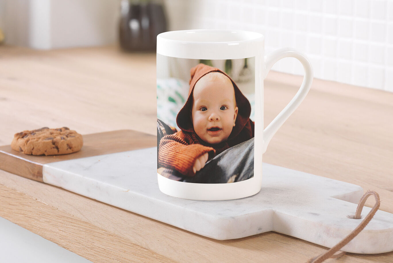 Eine Tasse mit einem liebevollen individuellen Foto, die auf einem Tisch steht, daneben ein Keks.