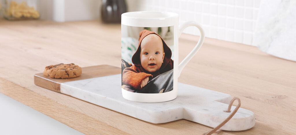 Eine Tasse mit warmem Getränk steht auf einem Holzbrett neben einem Keks