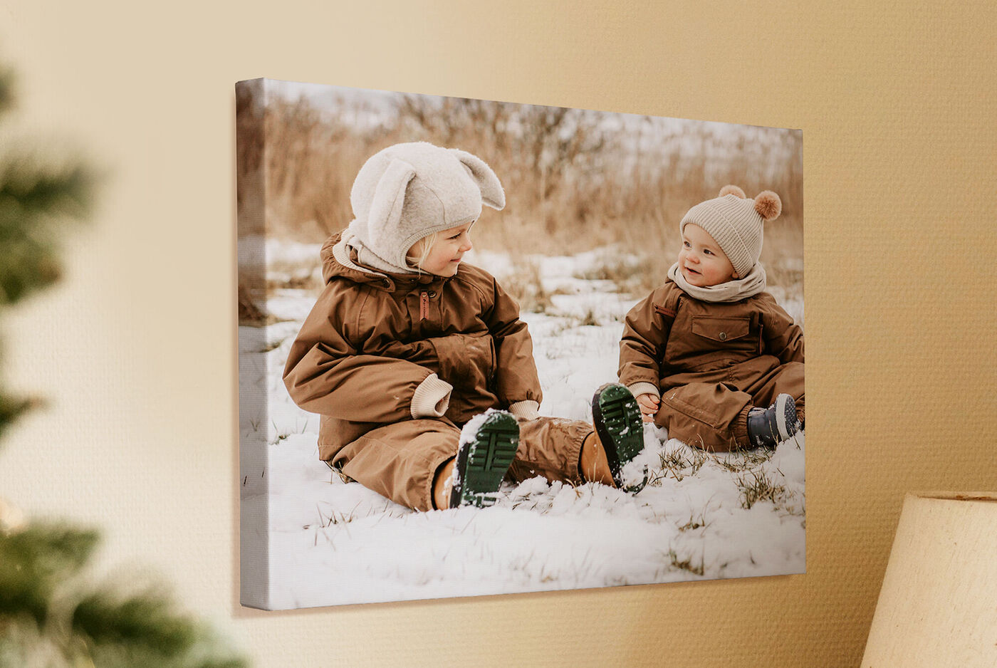 Zwei Kinder im Schnee sitzen in winterlicher Kleidung und spielen.