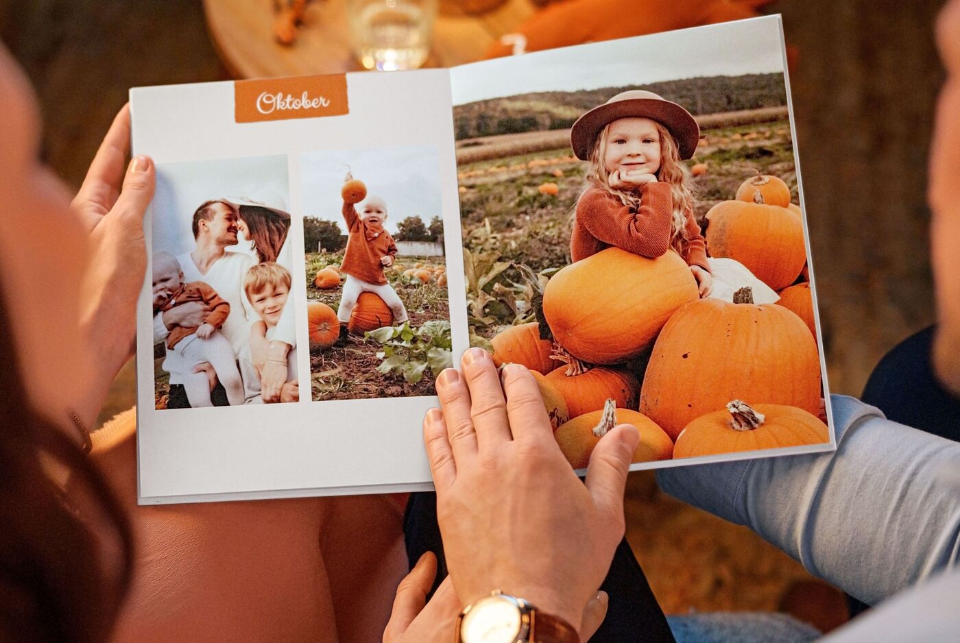 Eine glückliche Familie betrachtet ihr CEWE FOTOBUCH mit herbstlichen Motiven und Kürbissen.