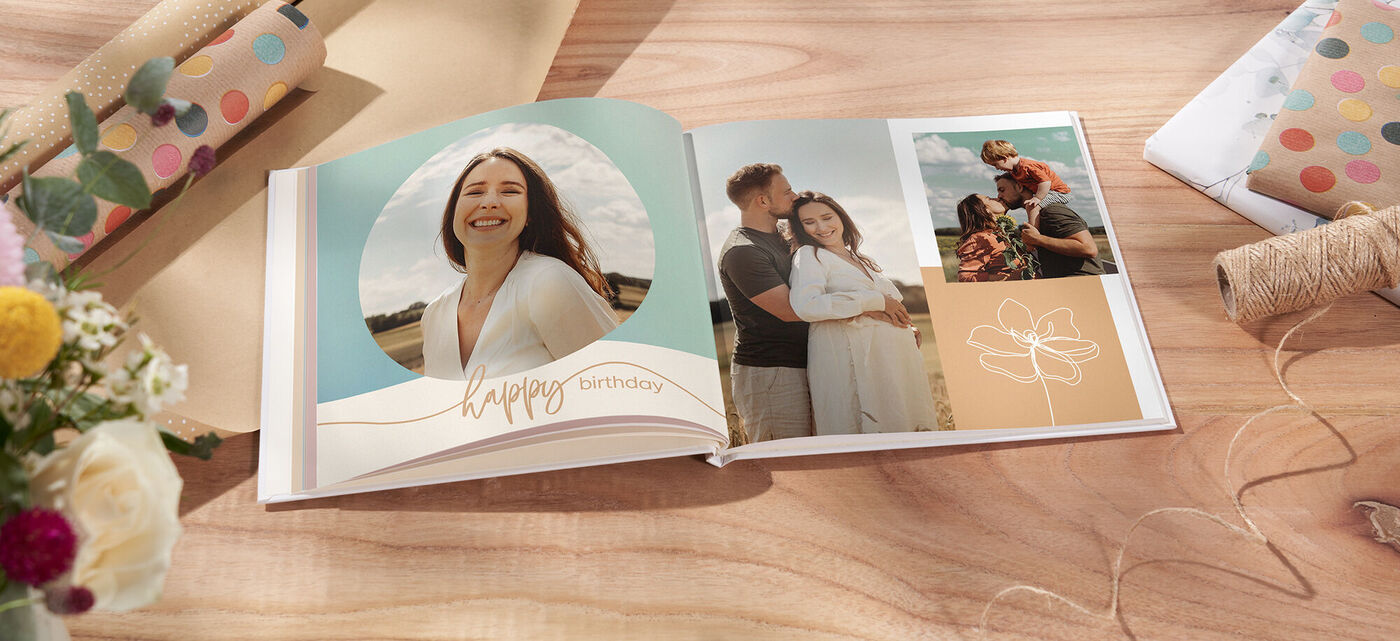 Ein offenes Fotobuch auf einem Tisch mit einem bunten Design, das fröhlich gestaltet ist. Es zeigt persönliche Erinnerungen und den Schriftzug 'Happy Birthday'.