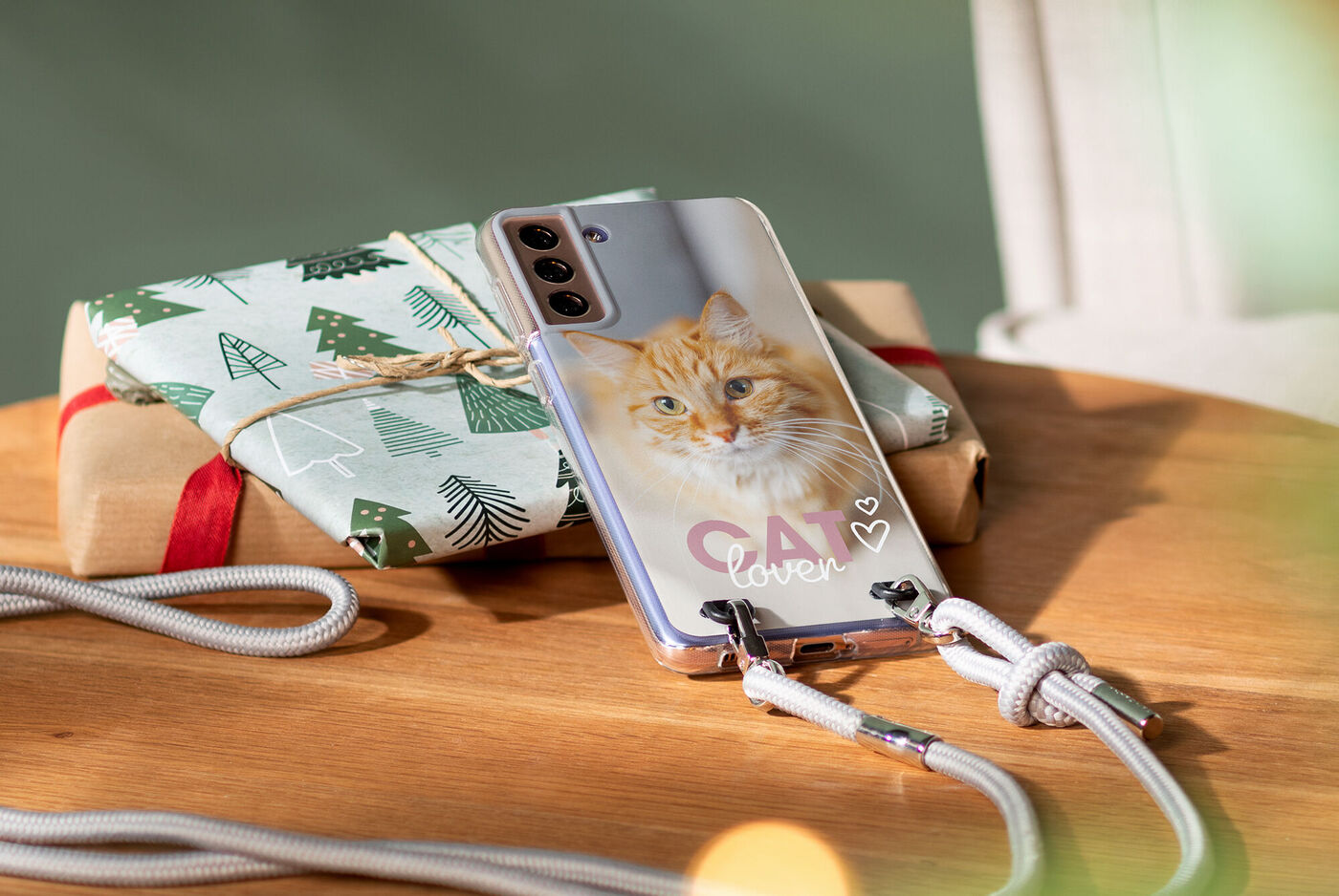 Handy mit Katzenmotiv und Geschenkpäckchen auf einem Tisch