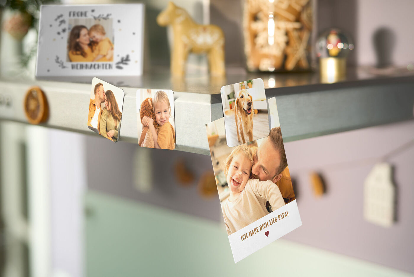 Personalisierte Magnete mit Fotos sind an einer Dunstabzugshaube befestigt. Im Vordergrund ein Magnet mit Hund und ein Familienfoto