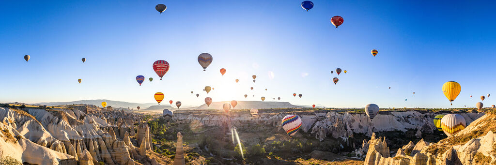 Bunte Heißluftballons vor blauem Himmel in Kappadokien